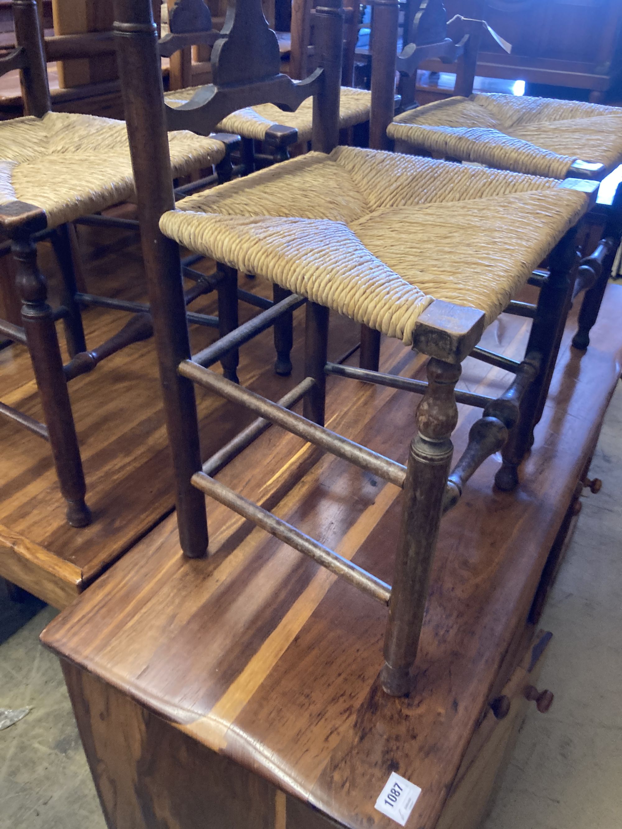 A set of four George III country oak rush seated chairs, with shaped back splat, turned supports and stretchers